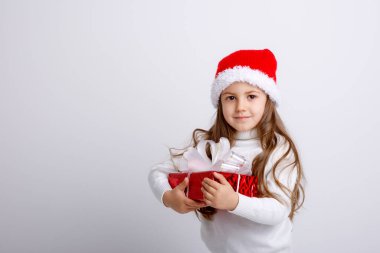 Noel Baba şapkasıyla ve hediye kutusuyla poz veren sevimli çocuk.