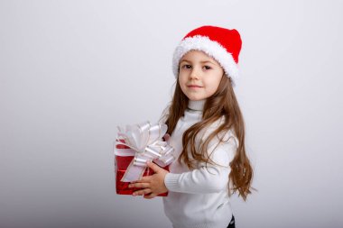 Noel Baba şapkasıyla ve hediye kutusuyla poz veren sevimli çocuk.