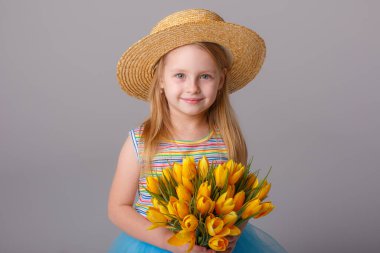 Stüdyoda sarı lalelerle poz veren sevimli küçük kız.