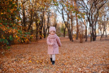 Sonbahar parkında eğlenen mavi gözlü küçük bir kız. 