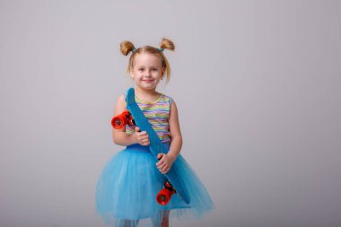 Küçük tatlı kız kaykay tutuyor.