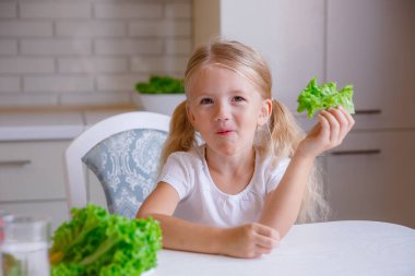 Sarışın kız mutfakta sebze yiyor.