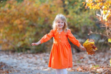 Güz parkında turuncu elbiseli güzel bir kız.