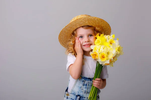 전반적으로 청바지를 꽃다발을 회색에 지푸라기 모자를 감정적 소녀의 — 스톡 사진