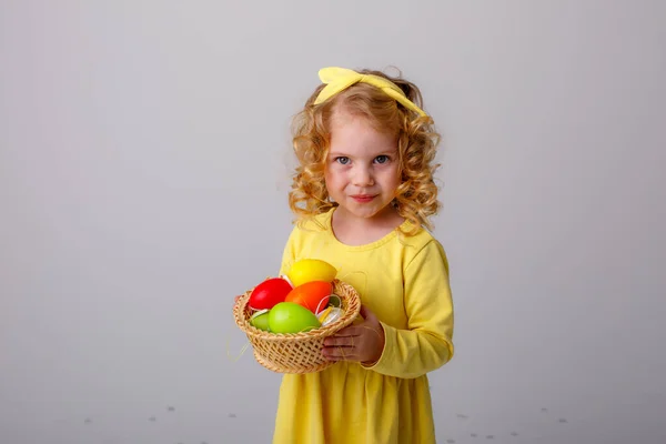 Küçük Kıvırcık Saçlı Bir Kız Gri Arka Planda Paskalya Yumurtaları — Stok fotoğraf