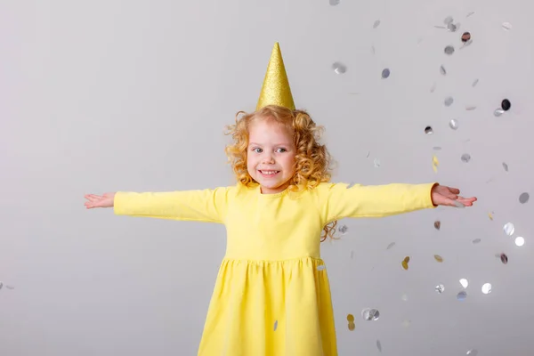 Μικρό Κορίτσι Ένα Κίτρινο Φόρεμα Αλίευση Κομφετί Γκρι Φόντο — Φωτογραφία Αρχείου