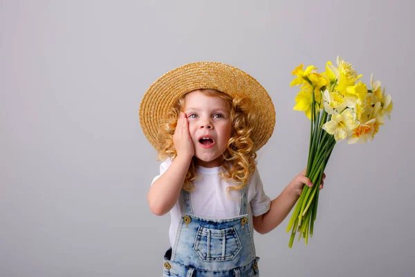 전반적으로 청바지를 꽃다발을 회색에 지푸라기 모자를 감정적 소녀의 — 스톡 사진
