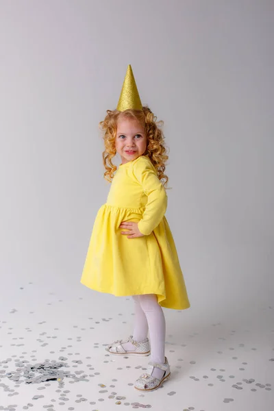 Niña Vestido Amarillo Captura Confeti Sobre Fondo Gris — Foto de Stock