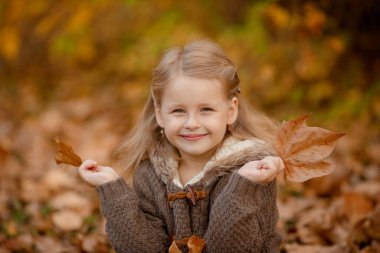 Sonbahar parkında poz veren neşeli çocuk