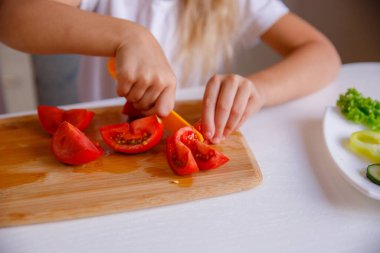 Çocuğun elleri domates kesiyor.