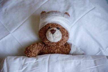 Hasta bir oyuncak ayı termometreyle yatakta yatıyor.