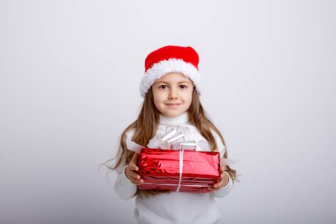 Noel Baba şapkasıyla ve hediye kutusuyla poz veren sevimli çocuk.