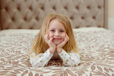 Sevimli küçük kız yatakta yatıyor.