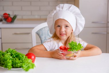 Aşçı şapkası takan sevimli küçük kız yemek yapmaya hazırlanıyor.