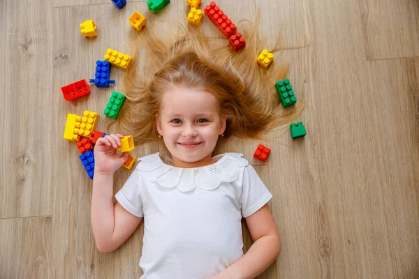 Uma Menina Loira Está Deitada Chão Entre Construtor Vista Cima — Fotografia de Stock