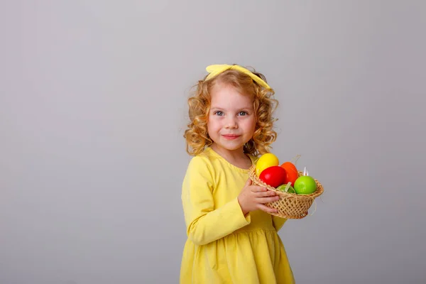 Küçük Kıvırcık Saçlı Bir Kız Gri Arka Planda Paskalya Yumurtaları — Stok fotoğraf