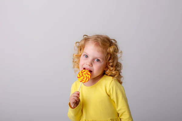 Kleines Lockiges Mädchen Posiert Mit Einem Lutscher Auf Grauem Hintergrund — Stockfoto