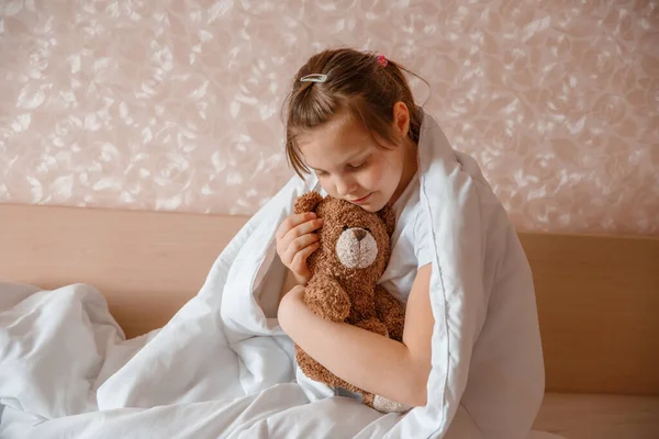 girl sitting with teddy bear at home