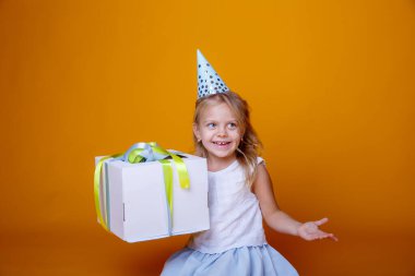 Doğum günü kızı stüdyoda turuncuya karşı hediye kutusuyla poz veriyor.