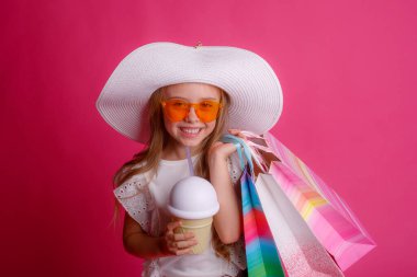 Stüdyoda pembe arka planda bir sürü alışveriş torbası olan küçük bir kız. 