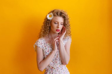 Makyajlı, kıvırcık saçlı ve saçında Daisy olan genç bir kadın. 