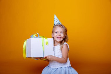 Doğum günü kızı stüdyoda turuncuya karşı hediye kutusuyla poz veriyor.