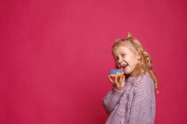 Fröhliches Kleines Mädchen Mit Einem Donut Auf Rosa Hintergrund — Stockfoto