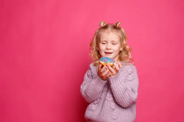 Fröhliches Kleines Mädchen Mit Einem Donut Auf Rosa Hintergrund — Stockfoto