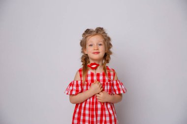 Beyaz arka planda komik gülümseyen bebek yaz elbisesi. Dudağında aksesuar olan küçük kız..