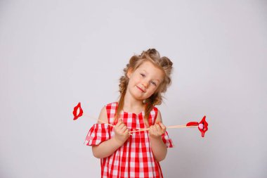 Beyaz arka planda komik gülümseyen bebek yaz elbisesi. Dudağında aksesuar olan küçük kız..