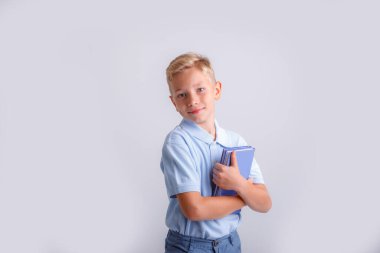 Gri arka plan kitabı olan küçük bir çocuk.