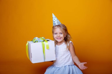 Doğum günü kızı stüdyoda turuncuya karşı hediye kutusuyla poz veriyor.