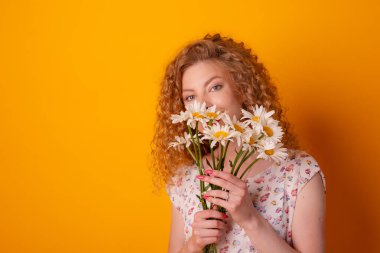 Turuncu arka planda papatya demeti olan bir kız.