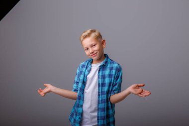 Çocuk gülümsüyor ve gri arka planda el ele tutuşuyor. Stüdyo çekimi