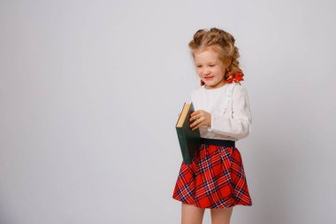 Okul üniformalı çocuk kitabı beyaz arka planda tutuyor. 