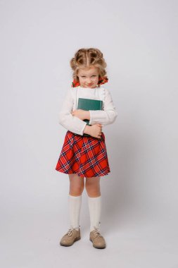 Okul üniformalı çocuk kitabı beyaz arka planda tutuyor. 