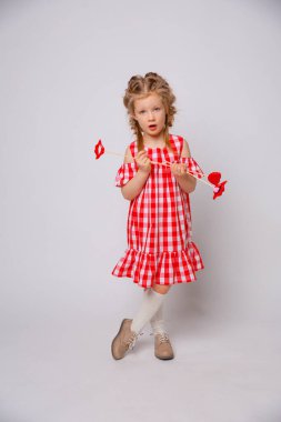 Beyaz arka planda komik gülümseyen bebek yaz elbisesi. Dudağında aksesuar olan küçük kız..