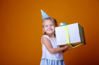 Doğum günü kızı stüdyoda turuncuya karşı hediye kutusuyla poz veriyor.