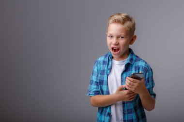 Akıllı telefon kullanan ekose gömlekli şık bir çocuk.