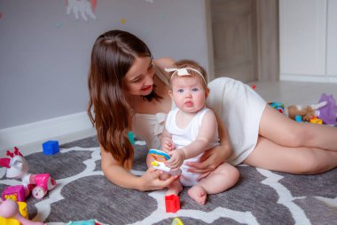 Güzel kız ve anne yerde oynuyorlar.