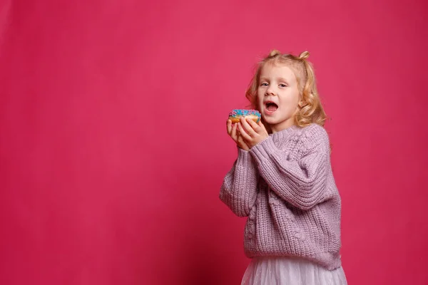 Fröhliches Kleines Mädchen Mit Einem Donut Auf Rosa Hintergrund — Stockfoto