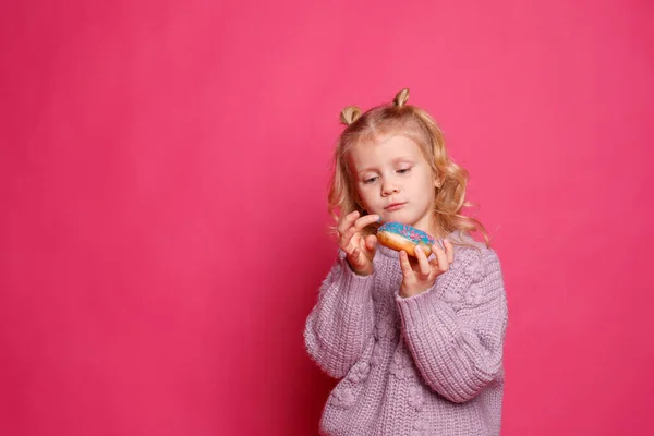 Fröhliches Kleines Mädchen Mit Einem Donut Auf Rosa Hintergrund — Stockfoto