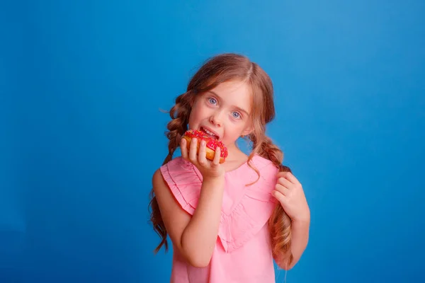 Ein Kleines Mädchen Posiert Mit Einem Donut Auf Blauem Hintergrund — Stockfoto