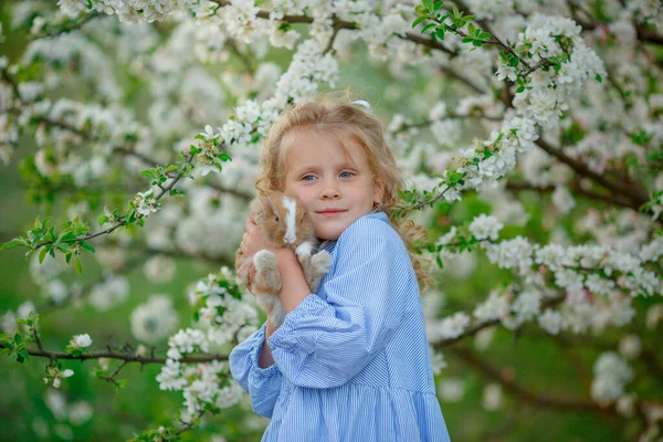 小さな女の子が手にウサギを抱いて春の花を咲かせ — ストック写真