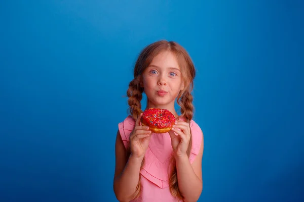 Ein Kleines Mädchen Posiert Mit Einem Donut Auf Blauem Hintergrund — Stockfoto