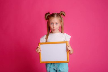 Boş bir çerçeve tutan bir kızın portresi, pembe bir arka planda, metin için yer 