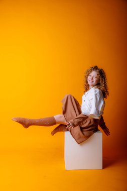 Stüdyoda turuncuya karşı poz veren tatlı genç kız.