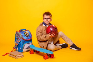 Sarı arka planda kitapları ve sırt çantası olan öğrenci.