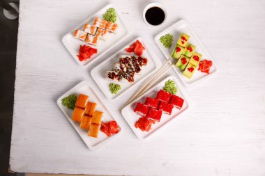 Suşi tahtadaki beyaz tabaklar üzerine kurulmuş.