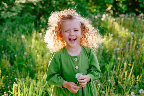 Pequena Loira Encaracolado Menina Vestido Verde Soprando Segurar Dente Leão — Fotografia de Stock